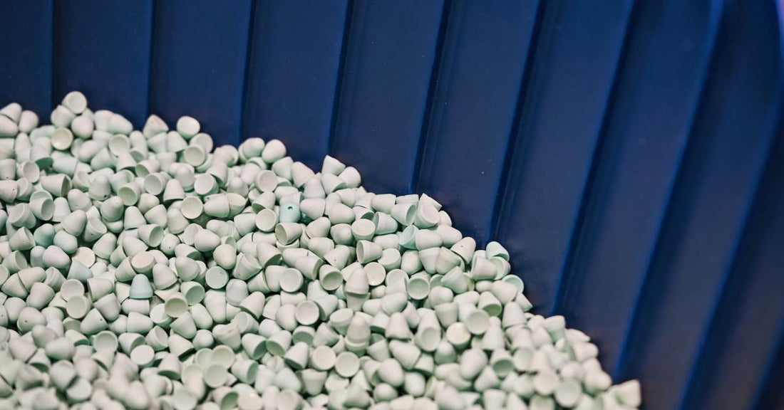 Small tear-drop shaped abrasive tumbling media inside a large blue finishing machine. The media is a light blue color.