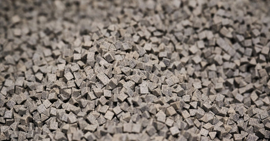 A large batch of tumbling media for a finishing machine. The media is gray and shaped like a triangle.