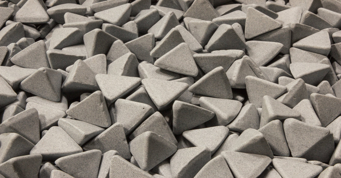A large pile of gray vibratory tumbling media for an industrial facility. The media is shaped like triangles.