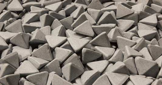 A large pile of gray vibratory tumbling media for an industrial facility. The media is shaped like triangles.