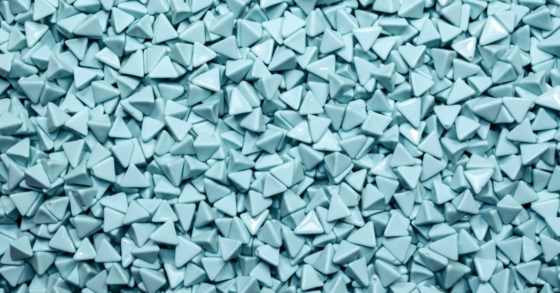 A large pile of light blue polishing media for a tumbling machine. The media is shaped like triangles.